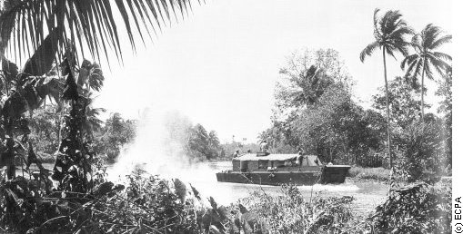 Military boat moving along a river in southeast Asia.