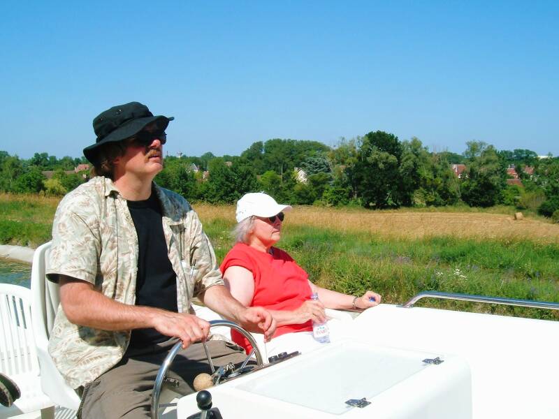 Bob at the wheel passing the village of Saint-Firmin-sur-Loire on the Canal Latéral à la Loire.