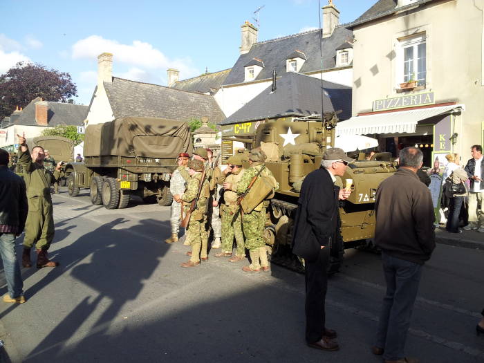 Actual U.S. forces join French and Belgian reenactors as U.S. forces and French Underground at Sainte-Mère-Église.