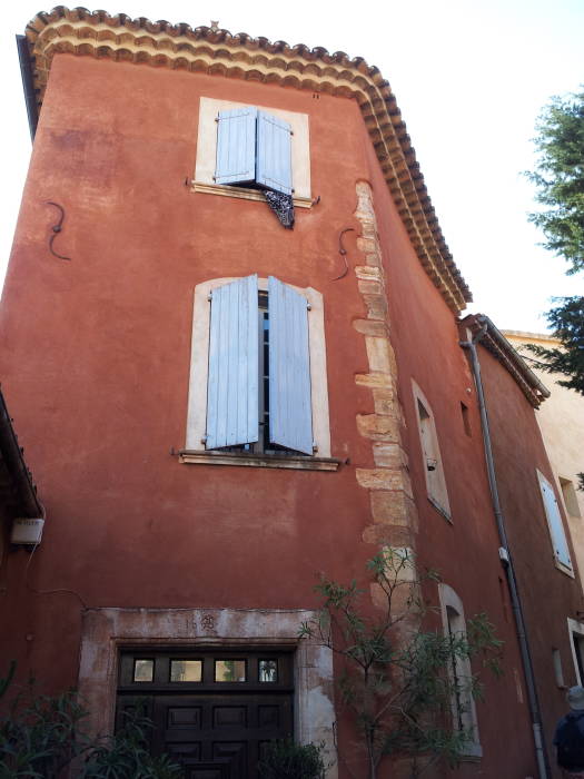 Ochre-colored building with light blue shutters in Roussillon.