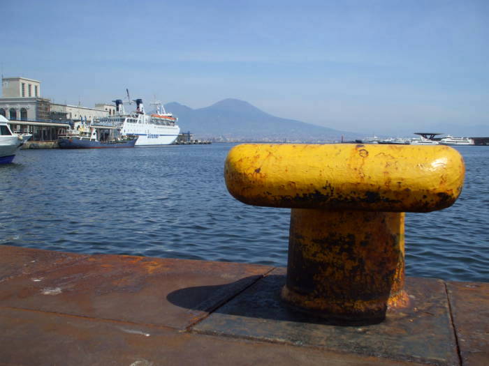 Large yellow bollard and large ferry in the Naples harbor.