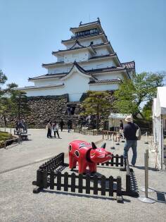 Akabeko the legendary obstinate cow in front of the tenshu or keep of Tsuruga Castle in Aizu-Wakamatsu.