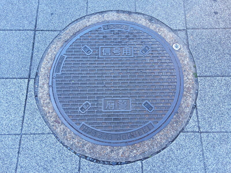 Standardized manhole cover in Kyōto, reading 'MPS 600 HOKUSEI' and 'FC-200'.