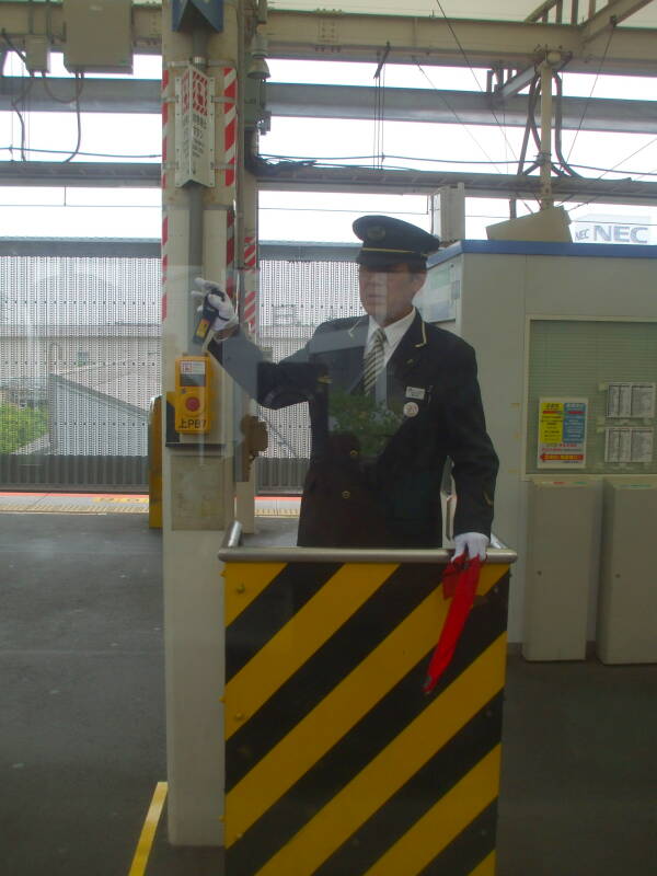 Uniformed platform attendant in a station between Kamakura and Tōkyō.