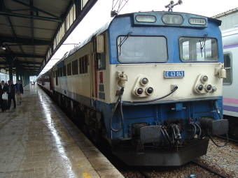 Blue and white locomotive pulling a Turkish passenger train.
