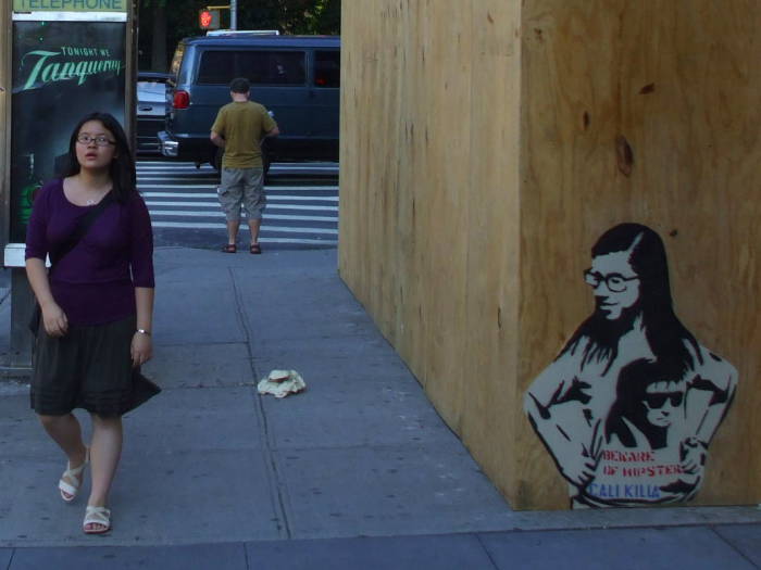 Hipster girl walking past stencil art of a hipster girl wearing a T-shirt bearing stencil art.  BEWARE OF HIPSTERS!