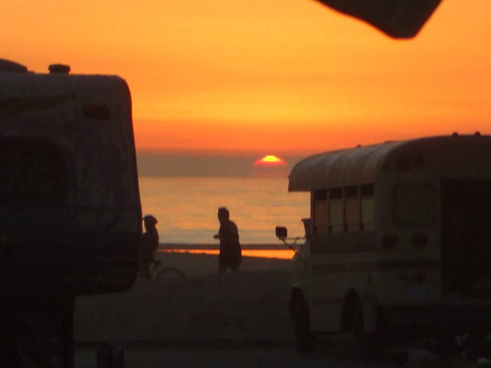Sunset over Venice Beach and the Pacific Ocean.  Man on a bicycle, a camper, and a bus.