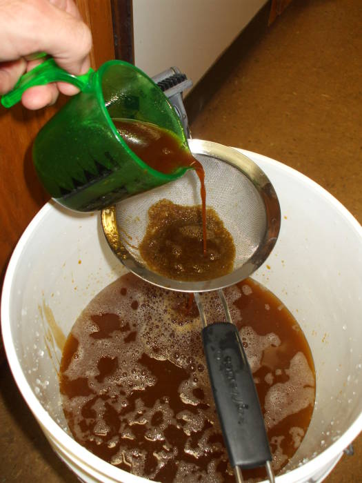 Beer brewing: putting the wort in the fermenter, filtering out the trub.