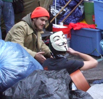 Occupy Wall Street protester wearing a Guy Fawkes Mask sold by the Time-Warner corporation.
