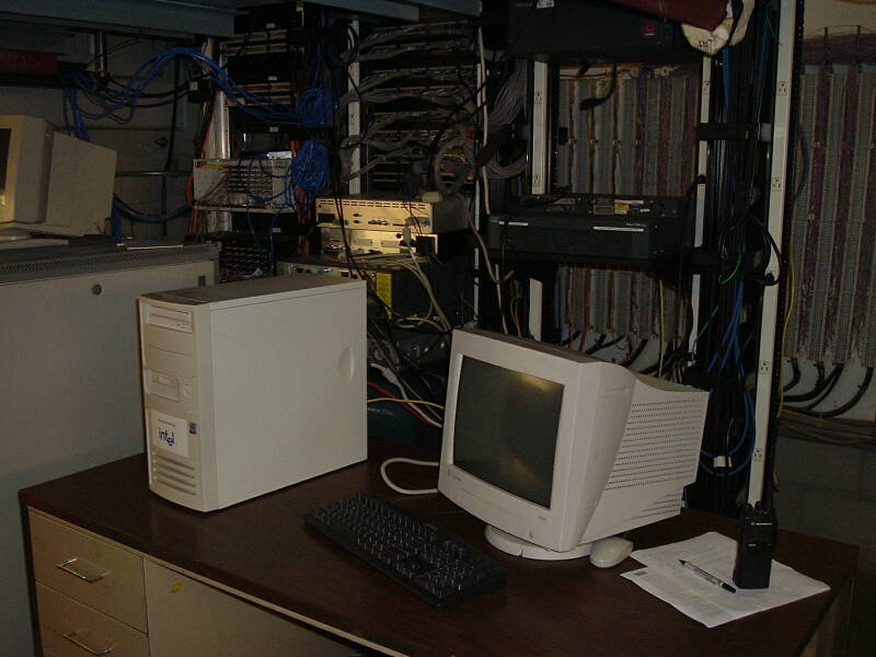 Telecommunications and networking room with racks of switches and routers, telco punchdown blocks, and a Linux firewall.