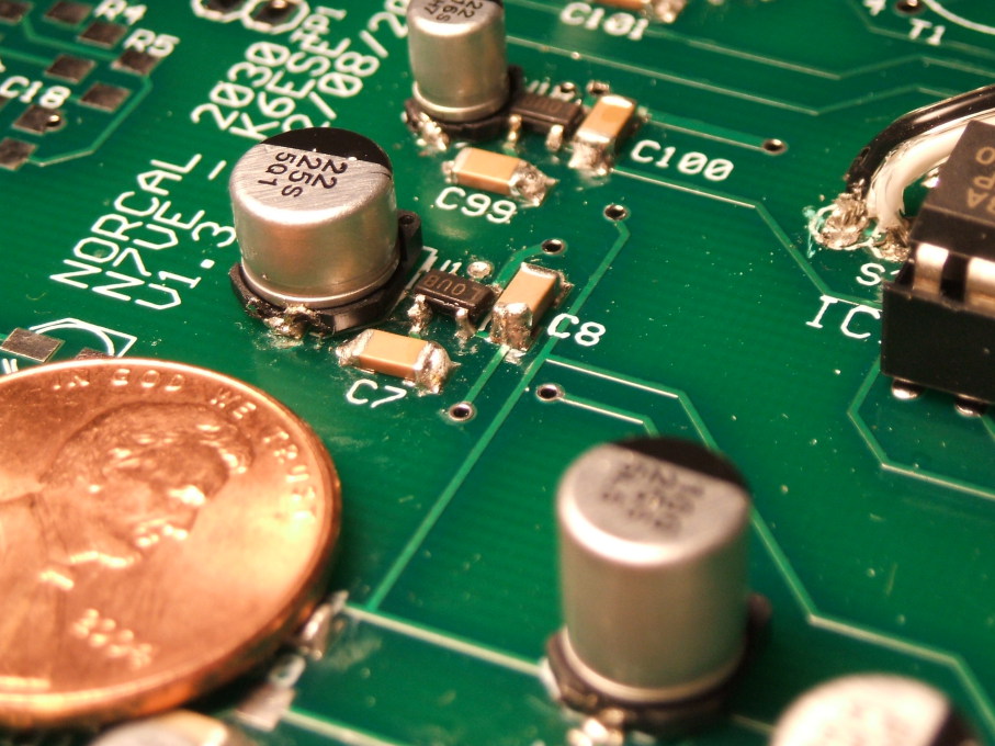 SOT-23 transistors, electrolytic capacitors, and other surface-mount components on a circuit board.