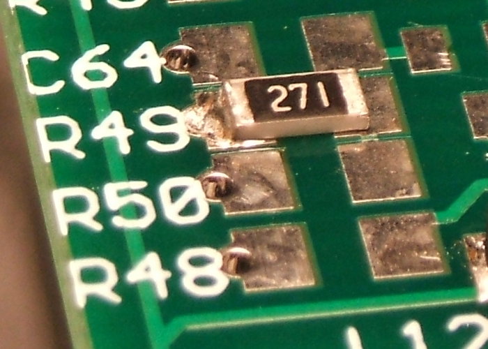 Close view of solder joints on a size 1206 surface-mount resistor being soldered in place on a circuit board.
