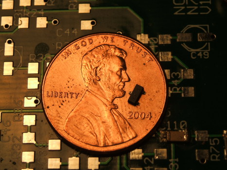 Surface-mount technology: three-terminal SOT-23 transistor package on a coin.