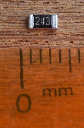 24 kilohm size 1206 surface mount resistor next to a millimeter scale.