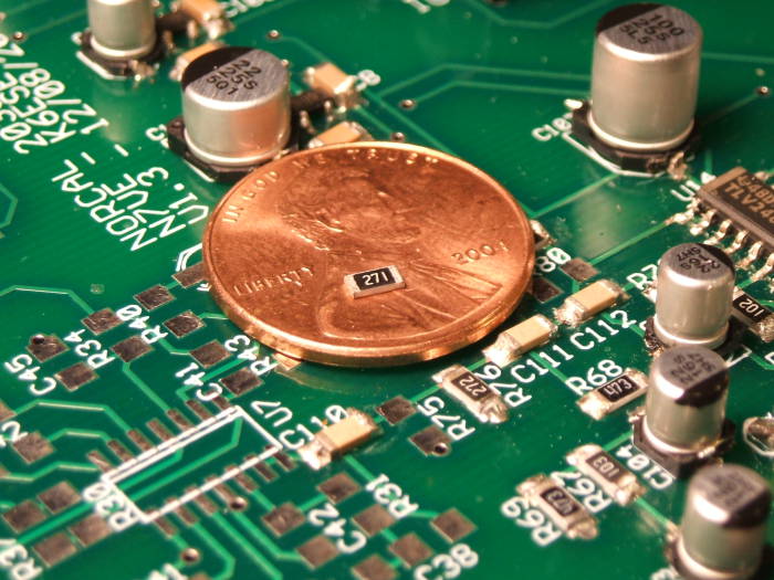 Surface mount resistor sitting on a coin, on the circuit board of an NC2030 QRP transceiver.