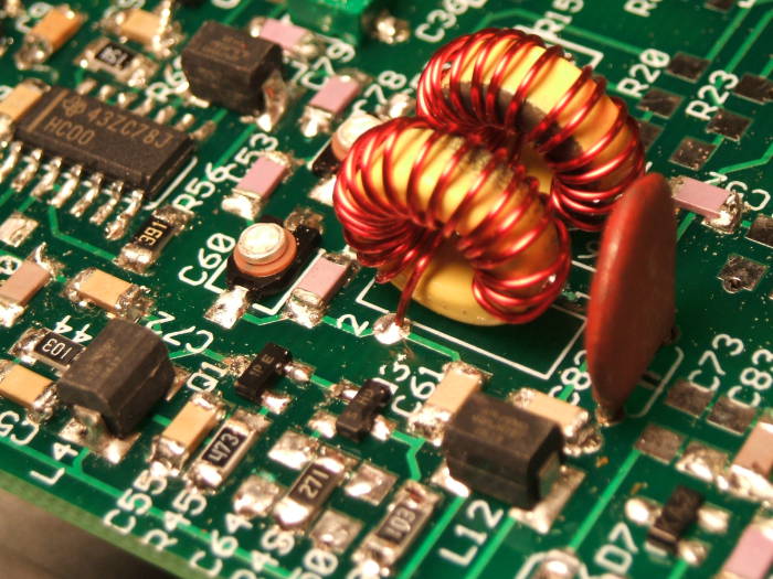 Two toroidal inductors and surface mount integrated circuits, transistors, resistors, and capacitors on the circuit board of an NC2030 QRP transceiver.