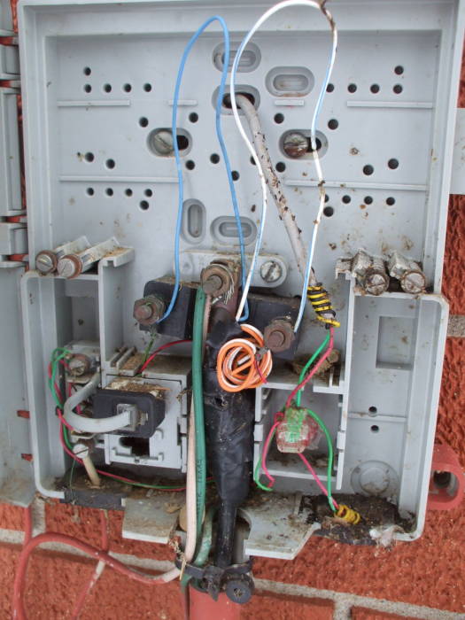 The telephone Network Interface Device is filled with dirt, debris and wasps' nests.