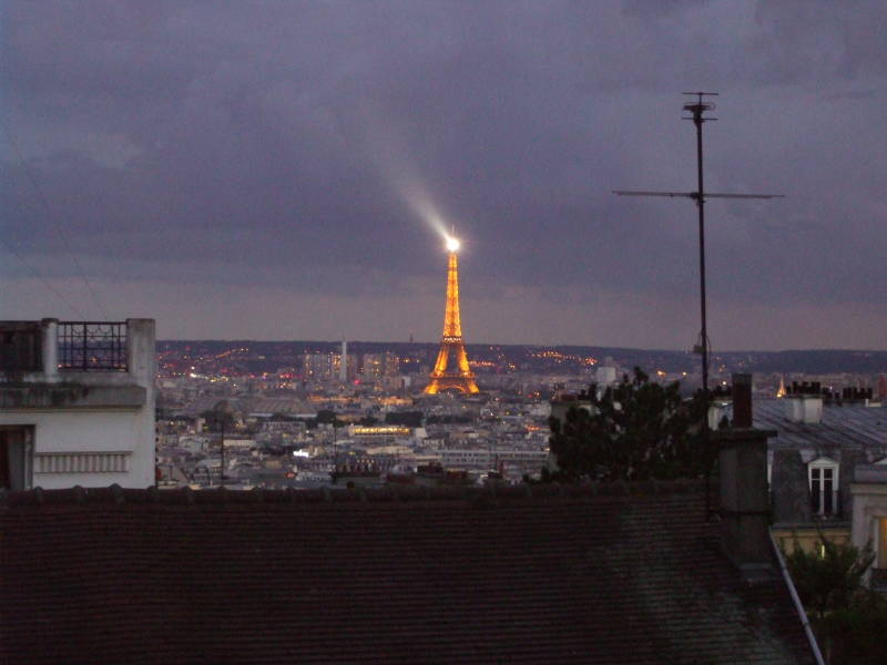 Eiffel Tower at night: Sparkling lights on the structure and a rotating beacon at the top.