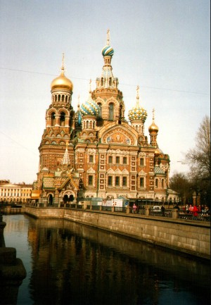The Church of the Spilled Blood, Sankt-Peterburg Russia, a Russian Orthodox cathedral with onion domes and colorful tiles, beside a canal.
