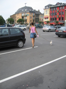 Cute girl walking a small dog across Bastogne's central square.