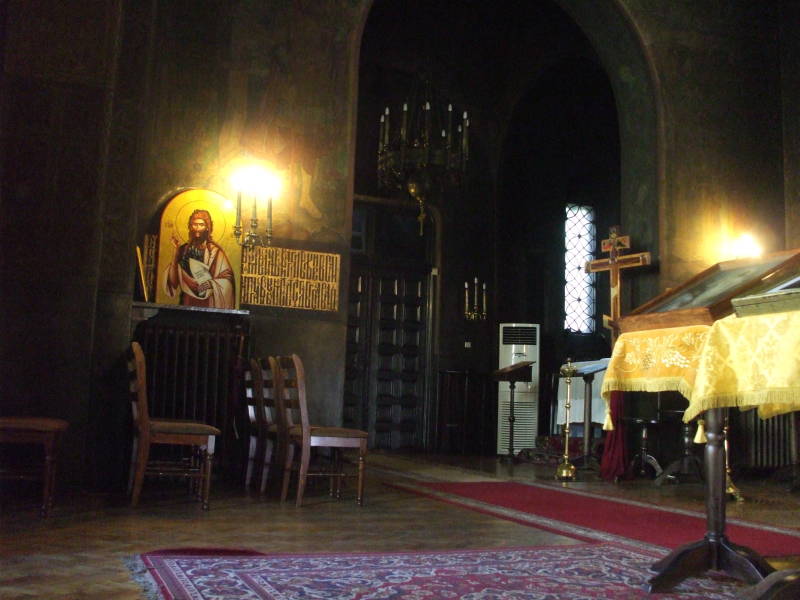 Interior of Church of Saint Nicholas in Sofia, Bulgaria.  Icon, candles, chairs, carpets.
