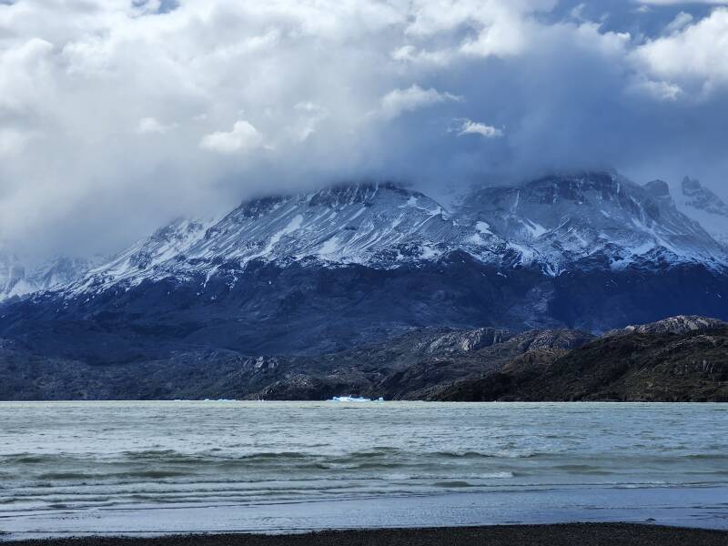 Blue fragments of a glacier floating in front of a mountain.