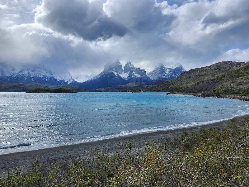 East end of Lago Pehoe, mountain peaks and dramatic clouds in the distance.