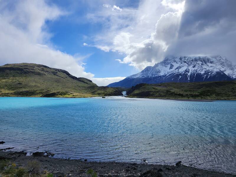 Turquoise lake, waterfall, snow-covered mountain.