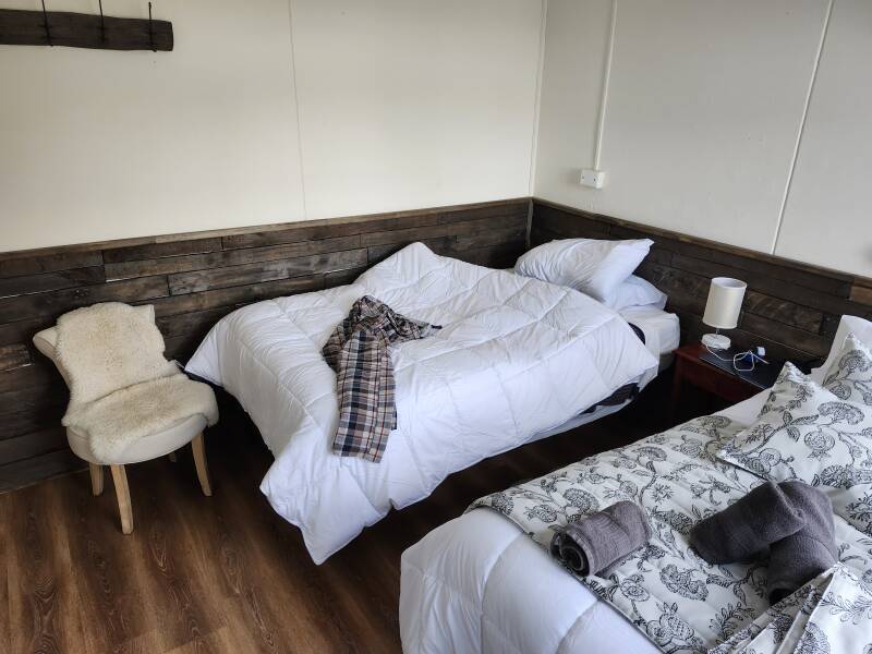 Room in Riverline Lodge — two double beds, nightstand, and chair.