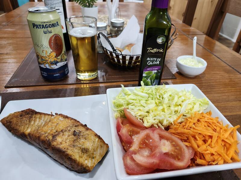 Patagonia Austral blond lager beer, salmon, salad, and bread rolls.