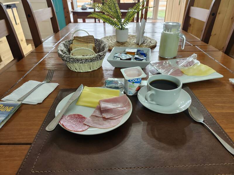 Breakfast: sliced meat and cheese, yoghurt, bread with butter and jam, and coffee.