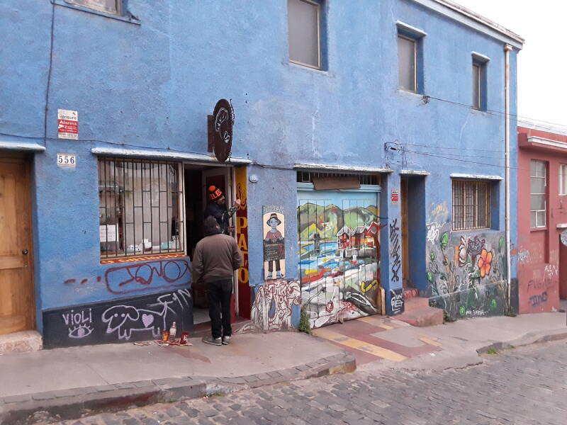 Shopkeeper painting a custom sign beside his door in Cerro Alegre area in Valparaíso, Chile