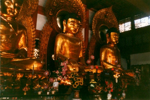 Three large gold statues in a Buddhist temple in China.