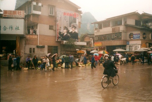 A man rides a bicycle through the muddy market square in Yangshuo, China.