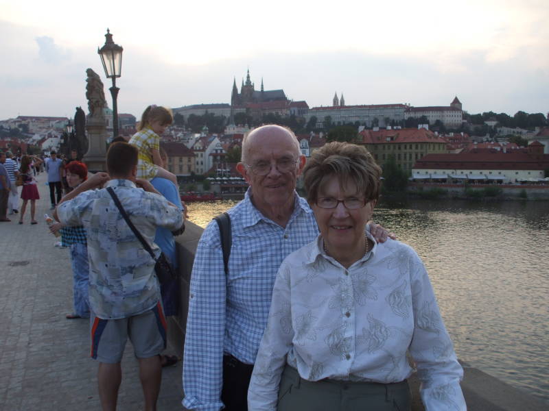 Two travelers on the Charles Bridge across the Vltava River in Prague.