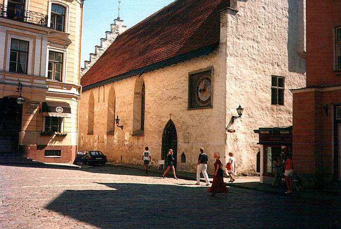 Beautiful women walk past the city market hall in the market square of Tallinn, Estonia.