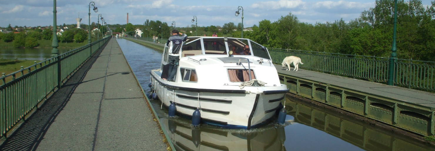 A rented canal boat crossing the Pont-Canal or Canal Bridge over the Loire River at Briare, in Burgundy, in central France.