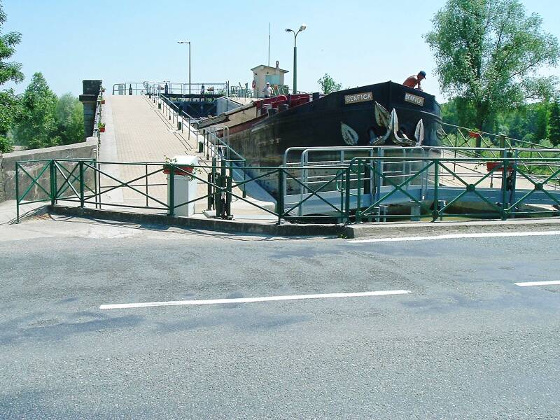 Large commercial barge passing through the high double lock and canal bridge at Guétin.