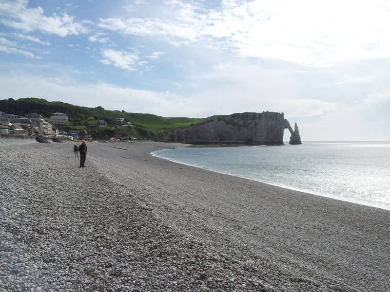 Man on the gravel beach below the chalk cliffs at Étretat, view to west.
