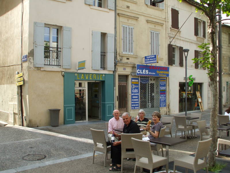 A happy group of travelers enjoying wine and cheese and bread outside a laverie in Avignon, in Provence, in southern France.