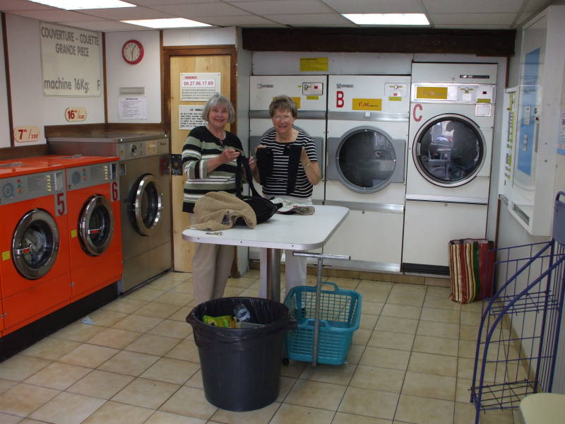 Happy travelers sorting their laundry in a laverie or lavomat in Avignon, in Provence, in southern France.
