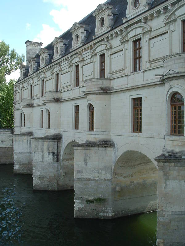 Château Chenonceau spans the Cher river on an arched stone bridge.