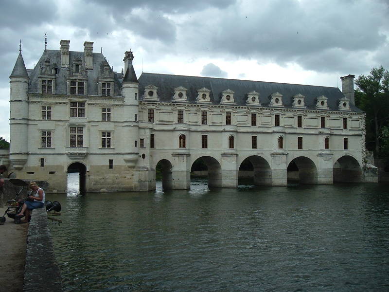 Château Chenonceau spans the Cher river on an arched stone bridge.