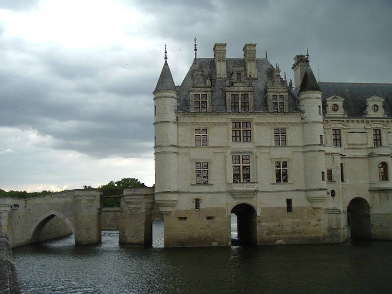 Château Chenonceau spans the Cher river on an arched stone bridge.