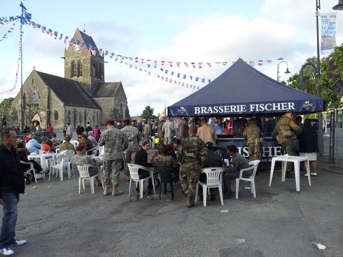 U.S. and NATO forces along with French and Belgian reenactors enjoy a musical program in Sainte-Mère-Église.