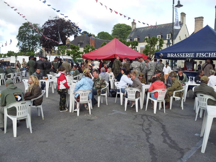 U.S. and NATO forces along with French and Belgian reenactors enjoy a musical program in Sainte-Mère-Église.
