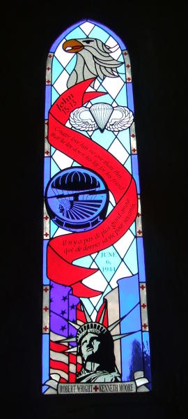 Stained glass window commemorating D-Day in the church at Angoville au Plain, in Normandy.  U.S. eagle, U.S. paratrooper emblems, U.S. and French flags, and the text of John 15:13 -- Il n'ya pas de plus grand amour que de donner sa vie pour ses amis. Greater love has no one than this, that he lay down his life for his friend.