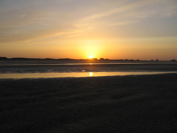 Sunset over Utah Beach.  Large Norman farm houses in the distance.