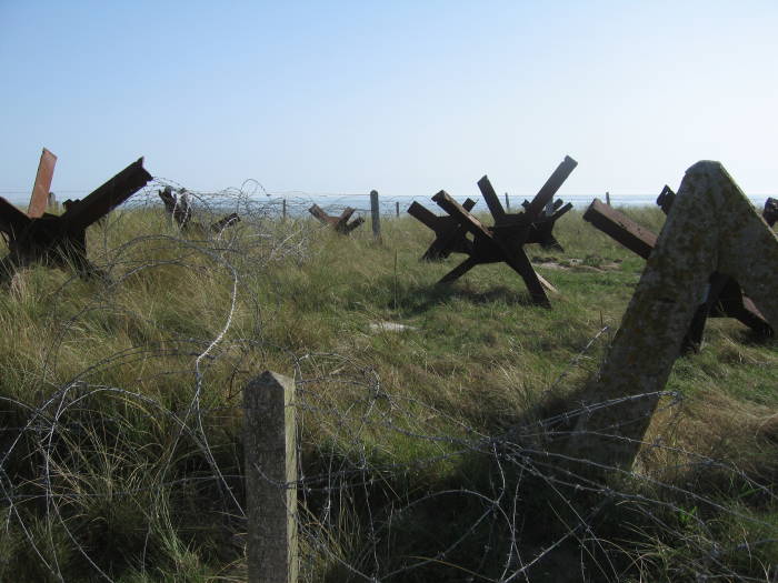 German defensive bunker and steel beach obstacles on Utah Beach, D-Day battlefield.