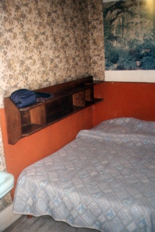 A room just like Jim Morrison's room at l'Hôtel de Médicis in Paris: The bed, shelves, and garish wallpaper.